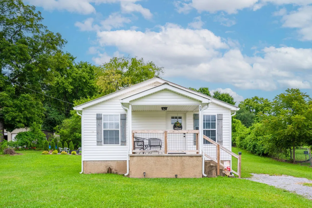 A welcoming view of the home’s front porch, adorned with a decorative wreath, overlooking a green lawn and surrounded by trees. The inviting setup suggests a peaceful retreat where families can relax, gather, and enjoy time together after days of exploration.
