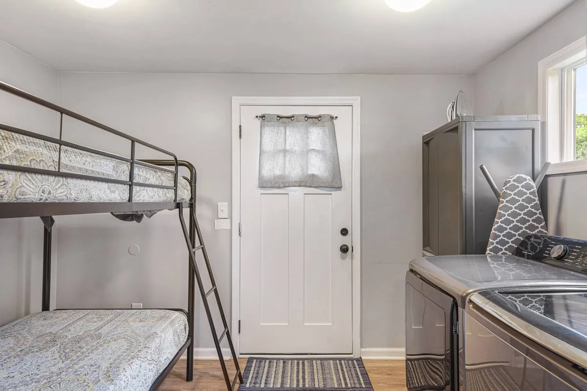A charming bunk bed area tailored for younger guests, featuring sturdy bunk beds, a window for natural light, and a practical washer and dryer tucked nearby. The space is functional yet inviting, ideal for families traveling with children.